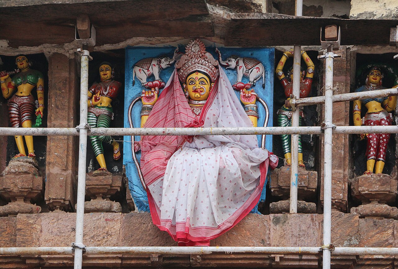 Color photograph of the Jagannath Temple tower at Puri, rising behind a wall.